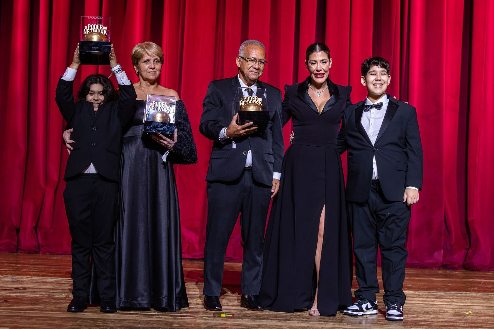 Cláudia e a família de Bruno Avelar recebem homenagem no palco do Poder do Network Awards, com os troféus nas mãos